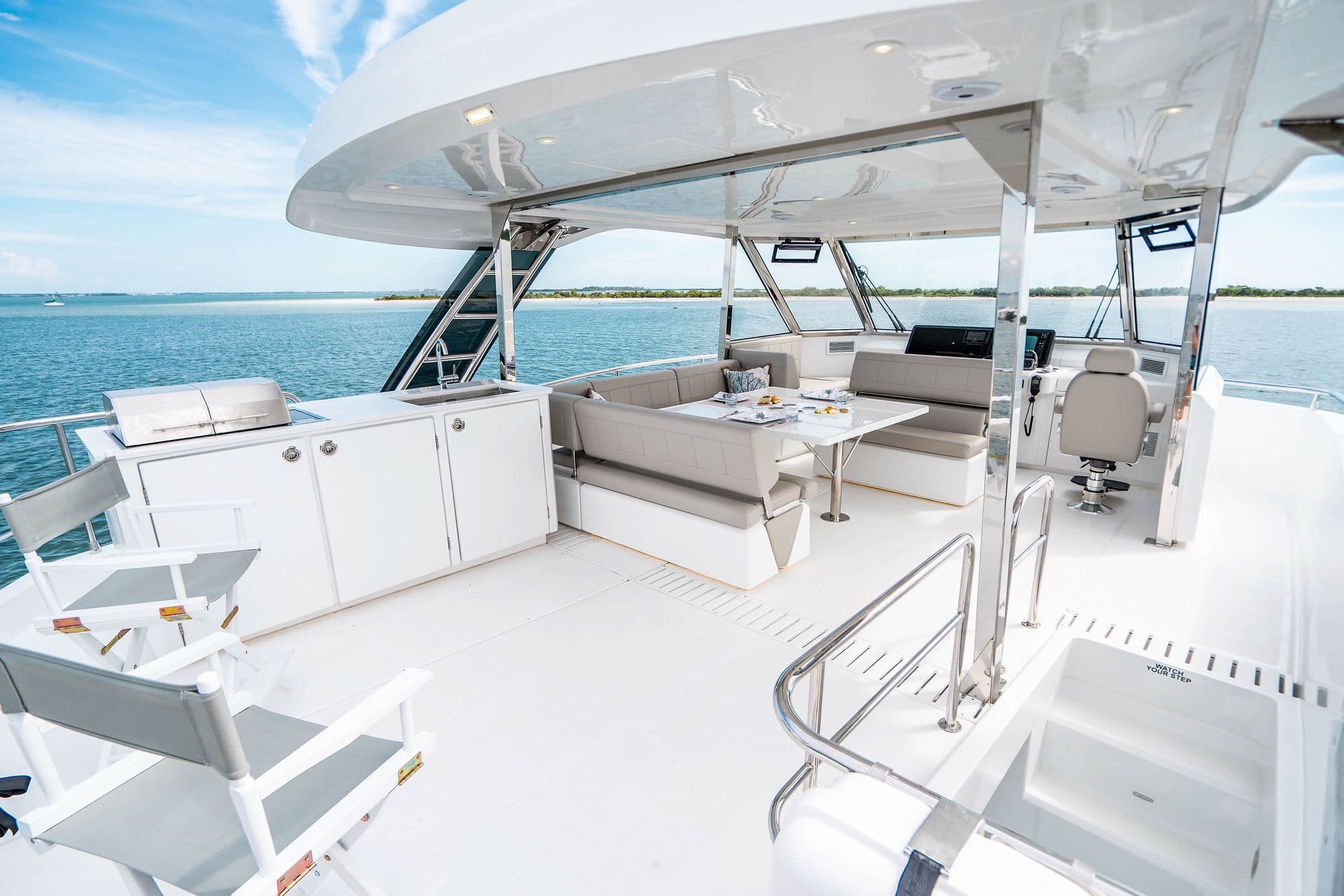 Open flybridge of the Aquila 54 Yacht with lounge seating and a dining table