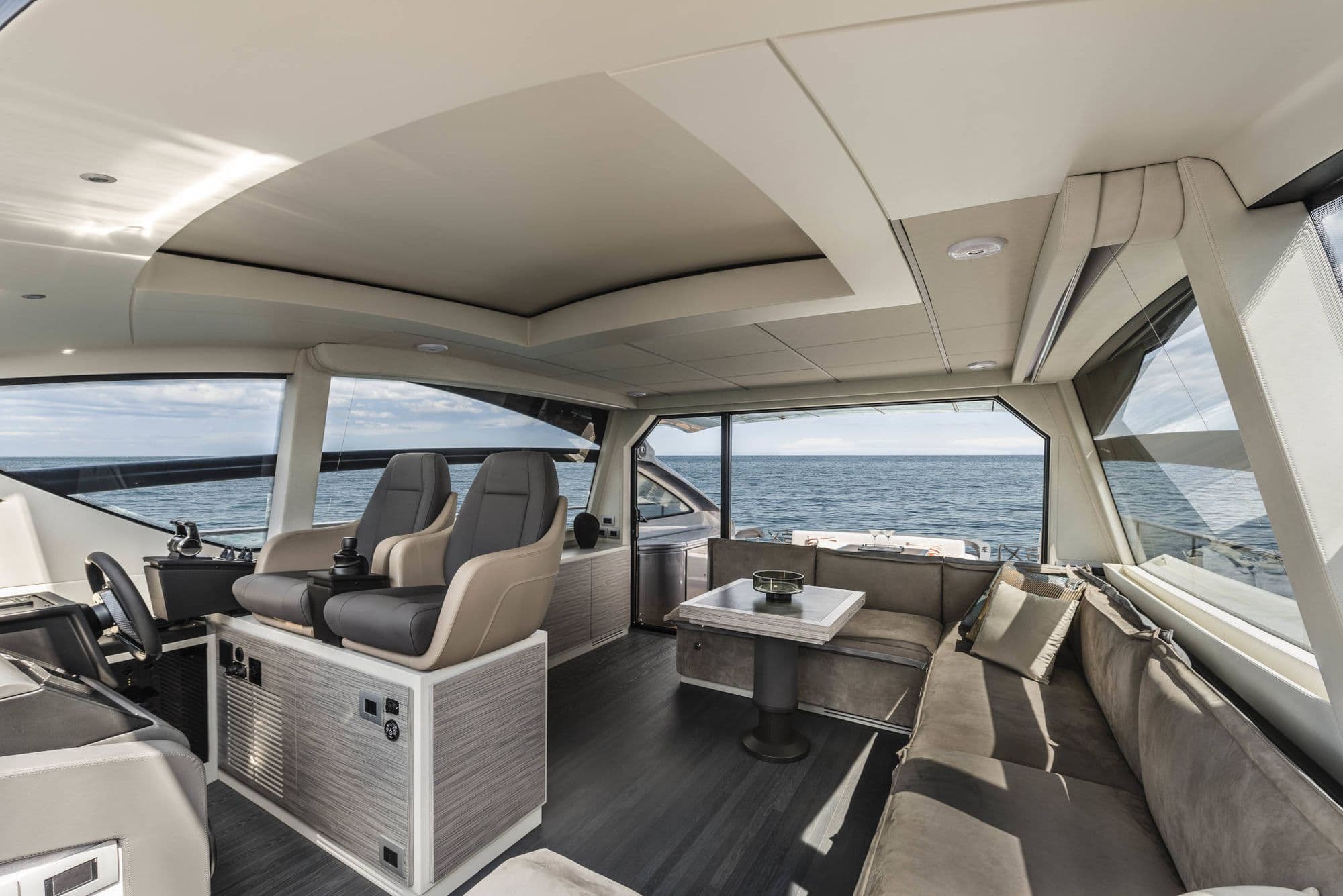 Helm and lounge area of the Pershing 6X with grey upholstery and big windows