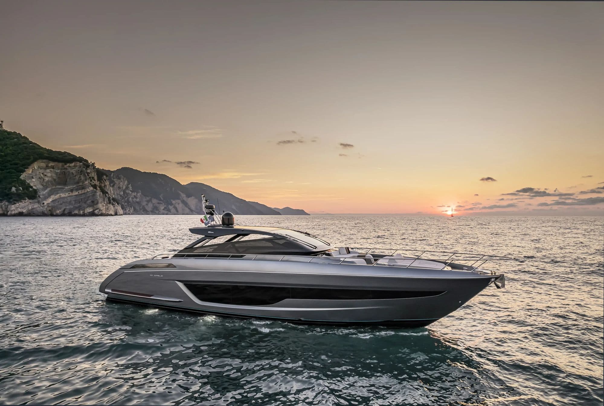 Riva 68' Diable in profile at sunset beside a rocky coast