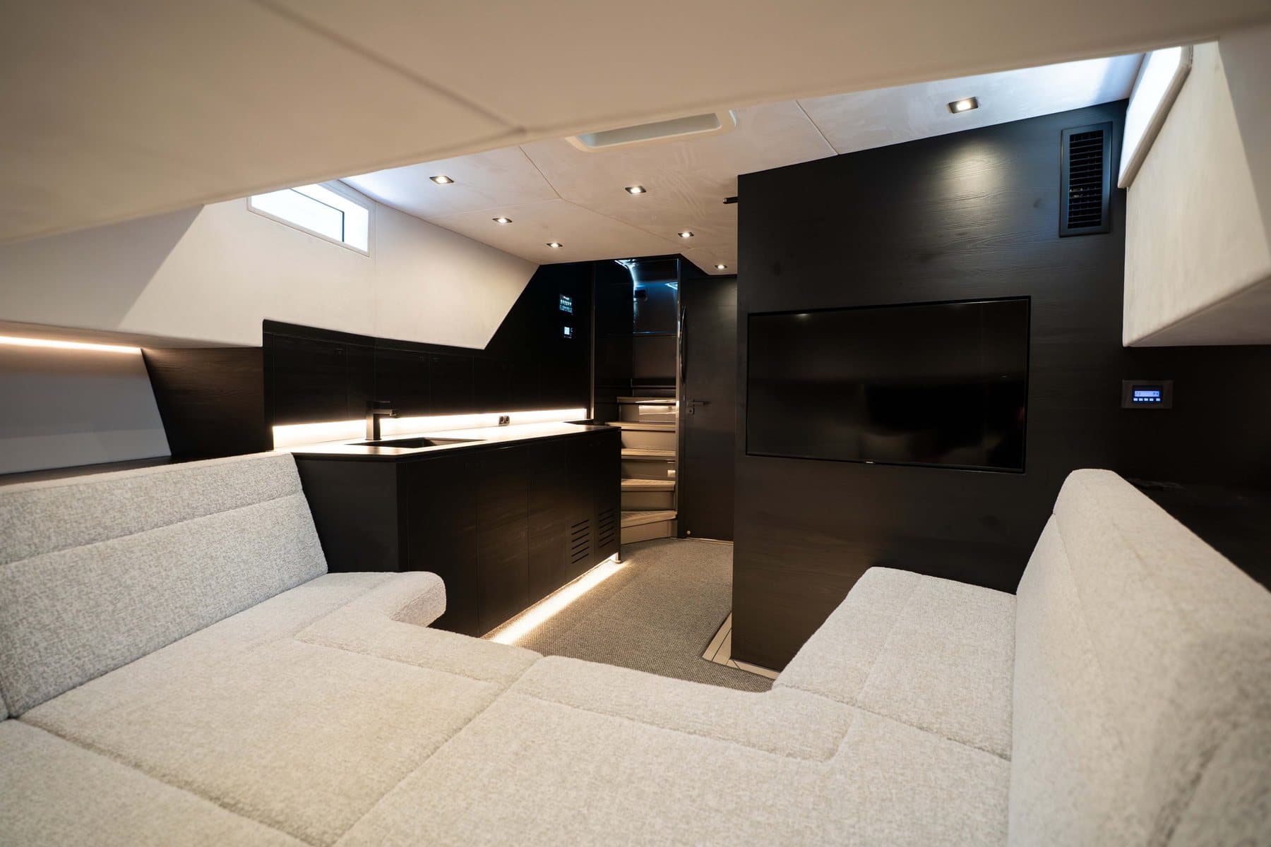 Lower salon of the Vanquish VQ58 with a wraparound sofa and dark joinery