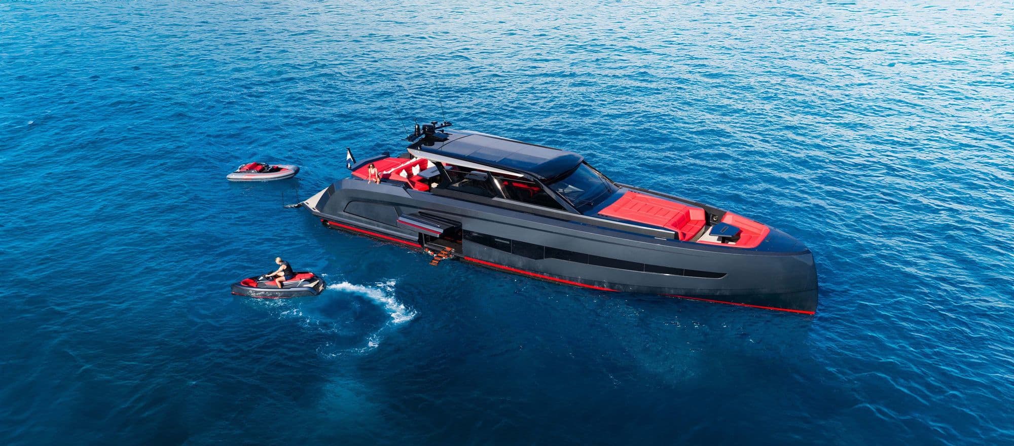 Aerial view of a dark Vanquish VQ70 with jet skis alongside