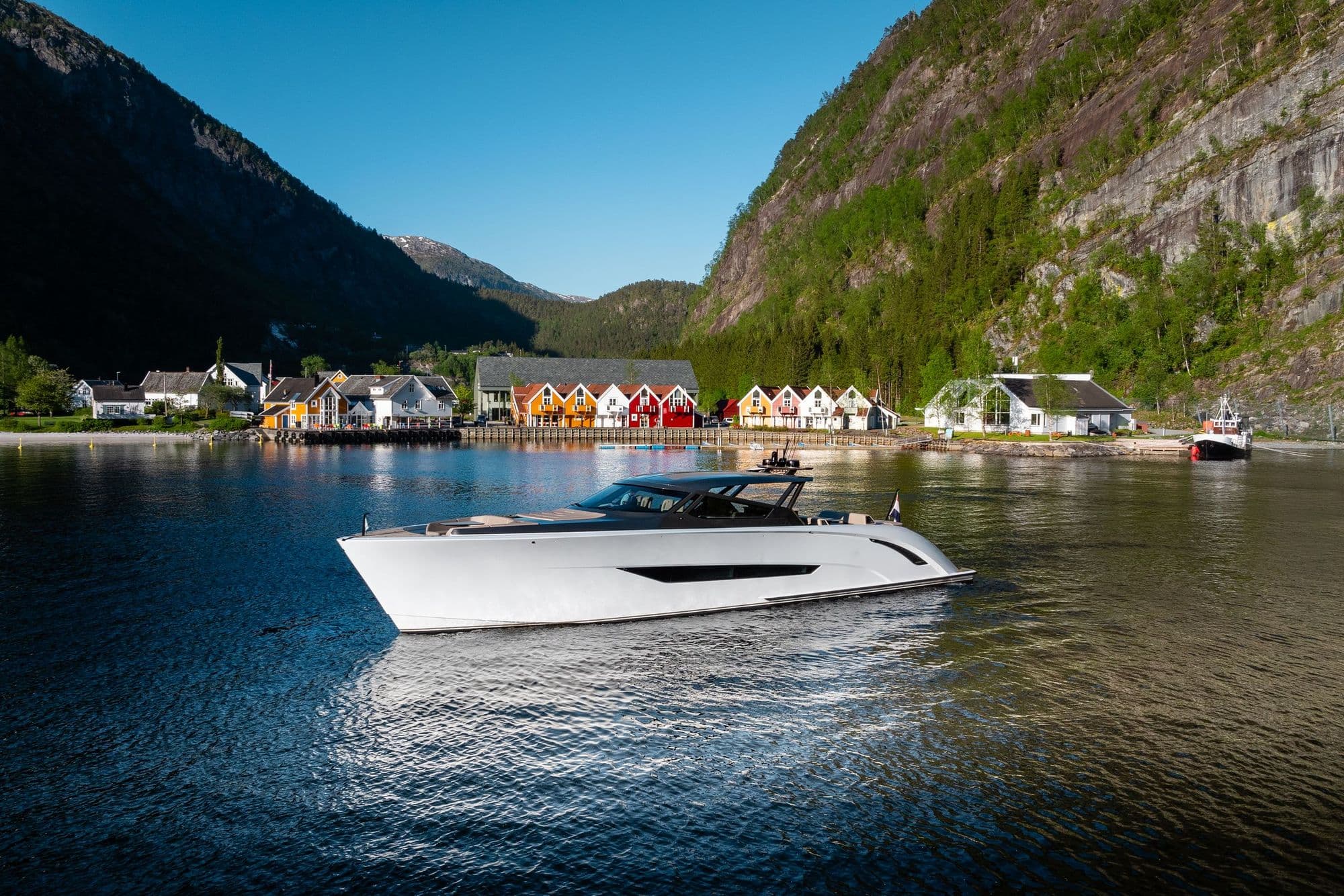 Wajer 77 at anchor off a waterside village