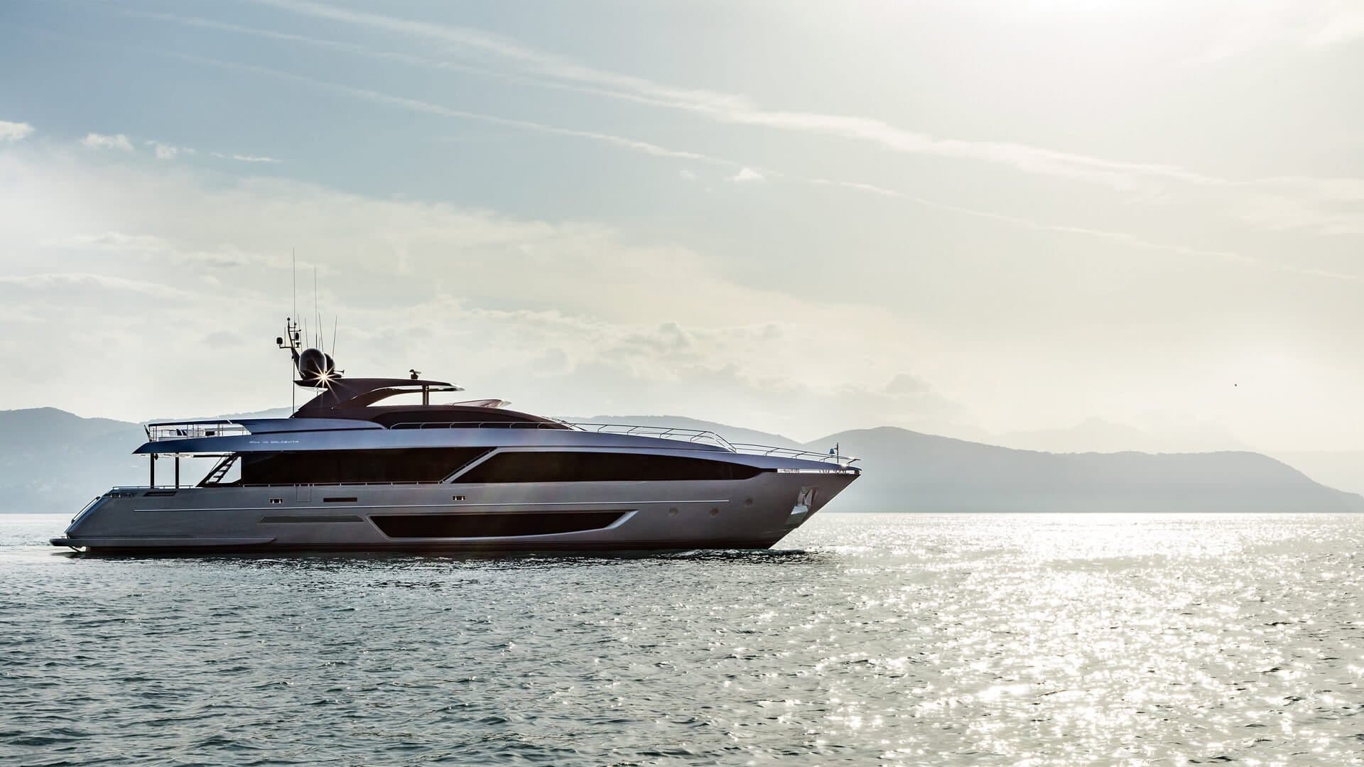Riva motor yacht on calm water with mountains behind
