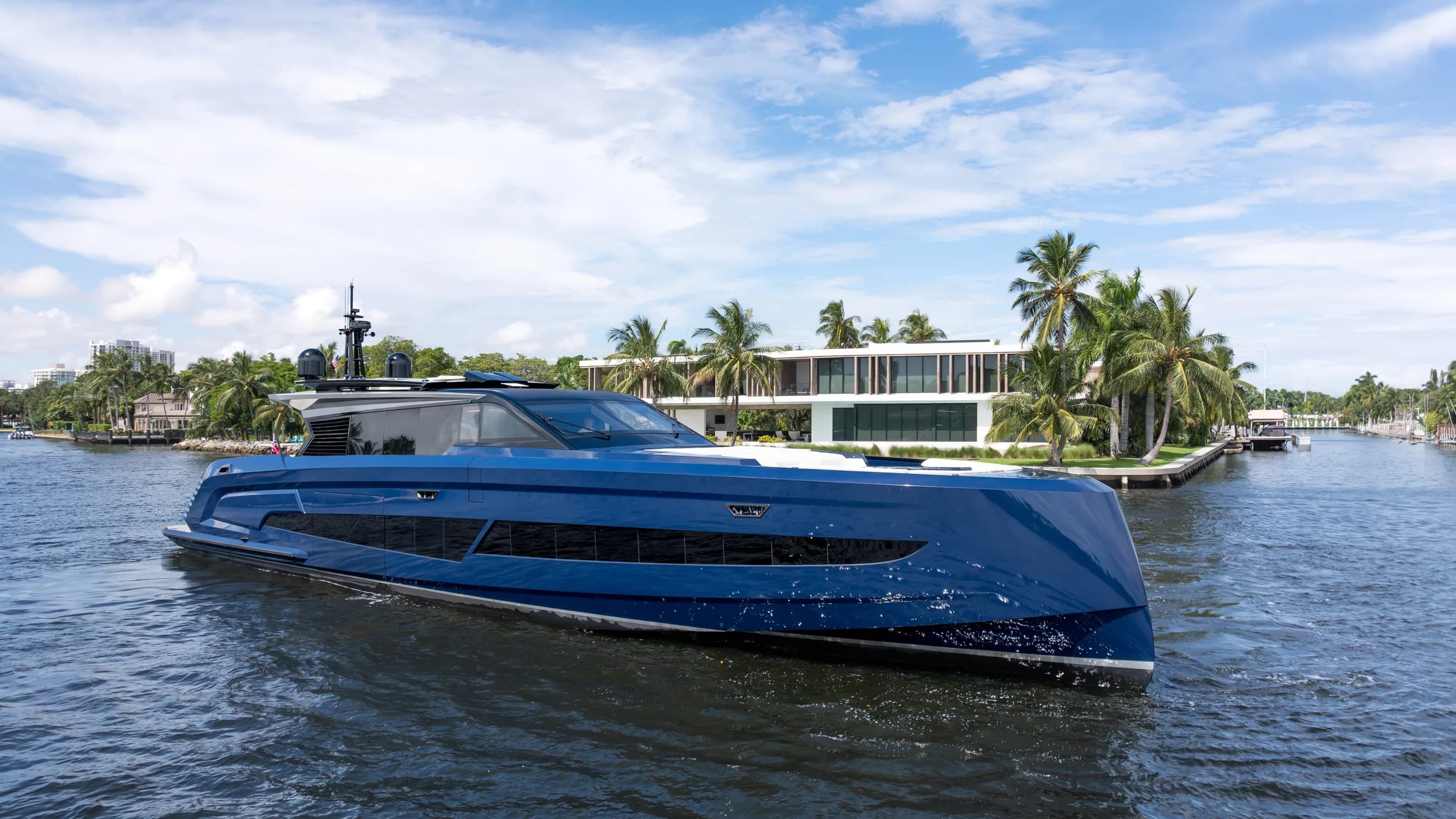 Vanquish VQ115 motor yacht cruising past waterfront homes