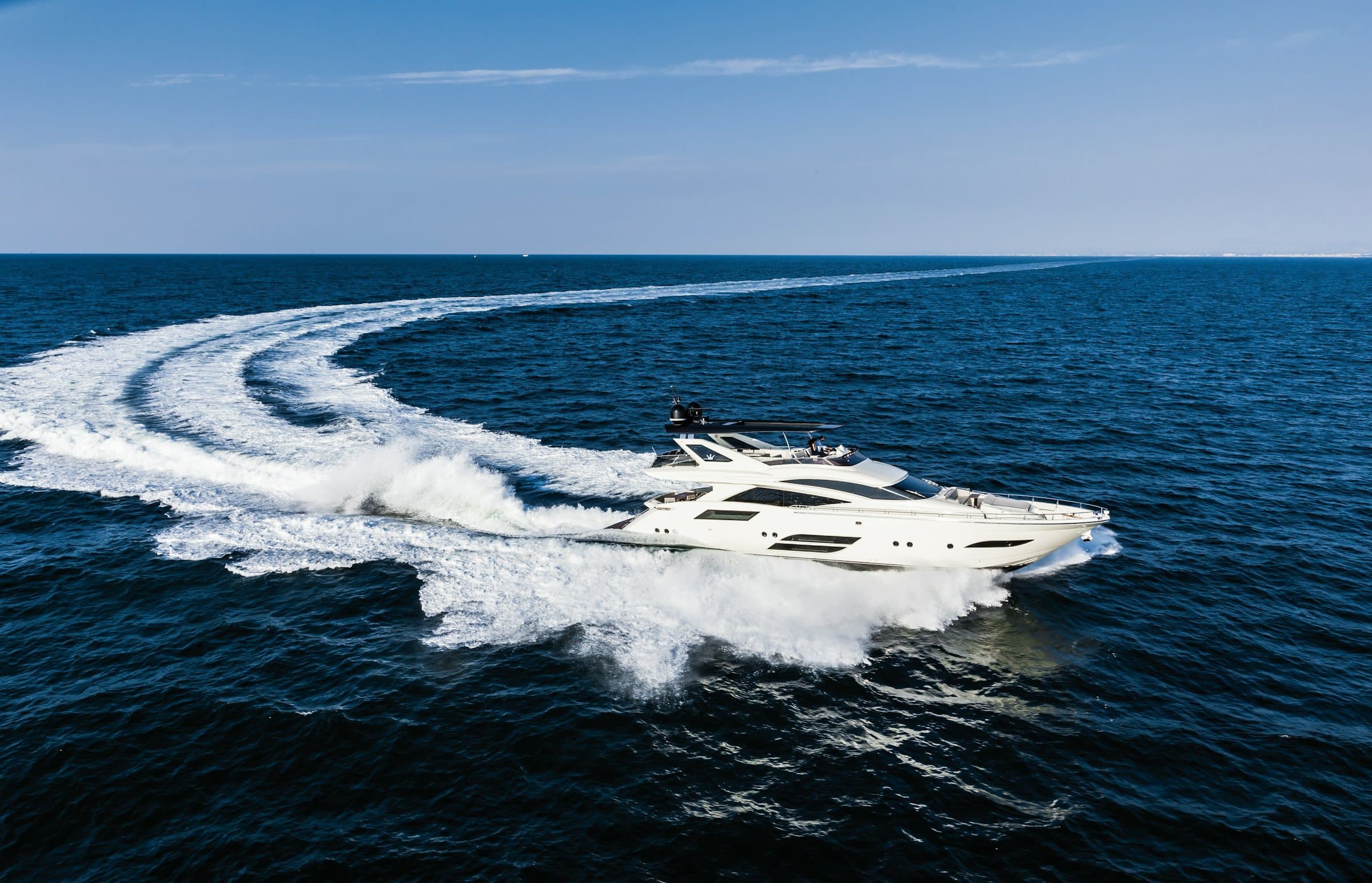 Modern flybridge motor yacht carving a turn at sea