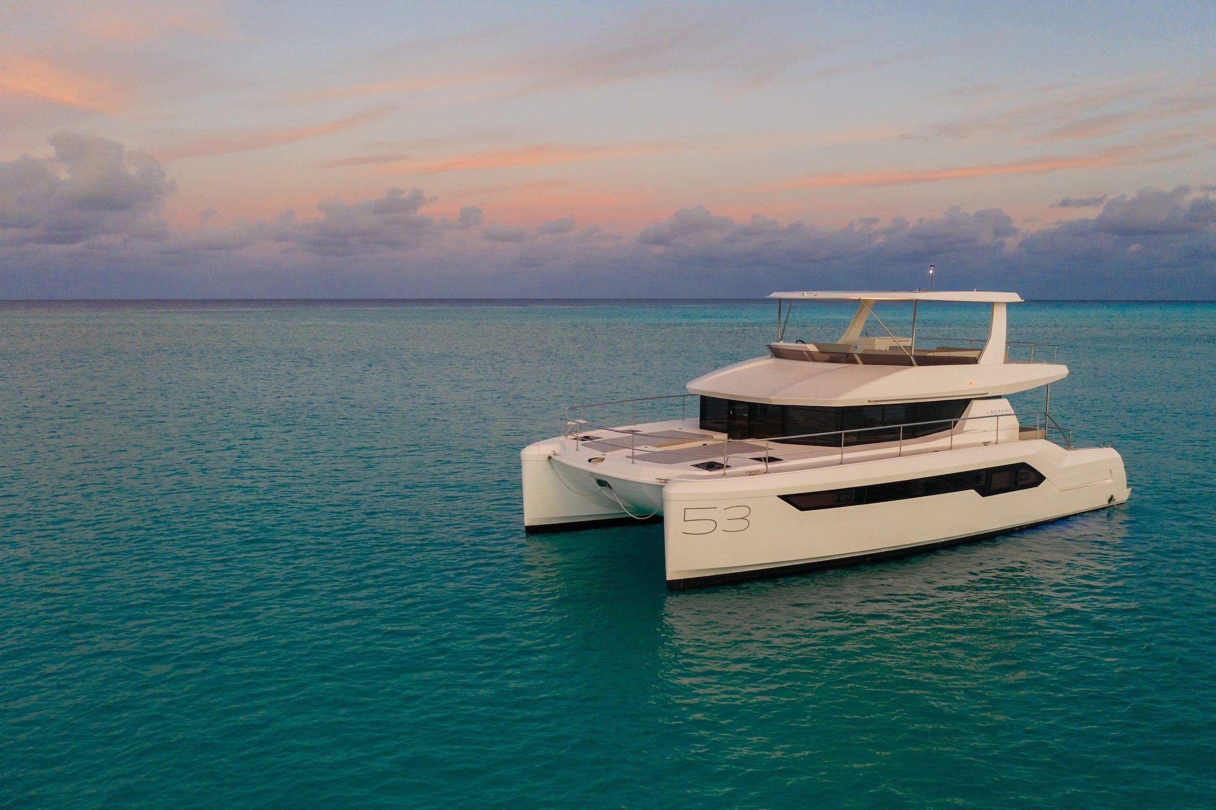 Leopard 53 Powercat power catamaran at anchor in turquoise water at sunset