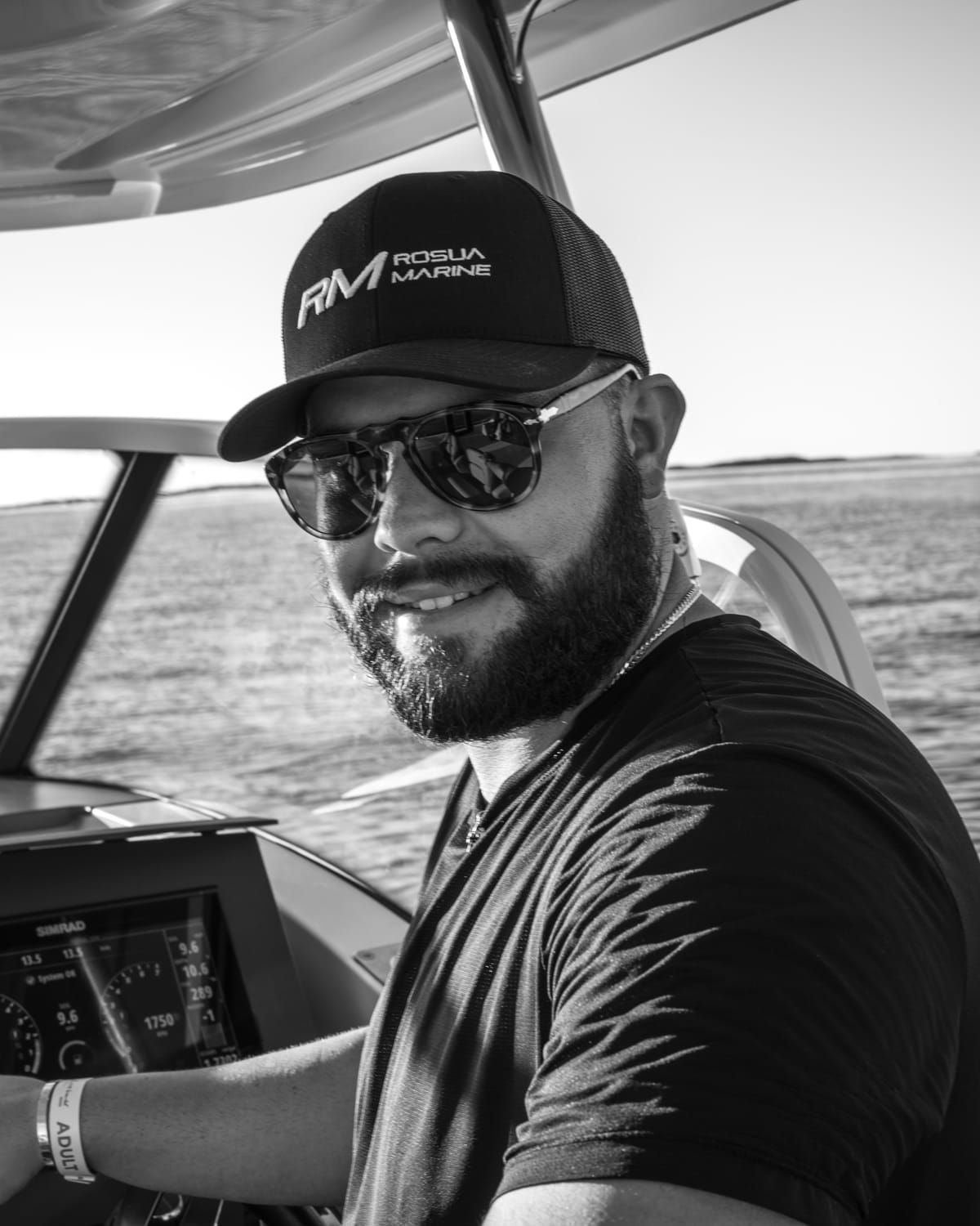 Daniel Rosua at the helm of a motor yacht, wearing an RM Rosua Marine cap